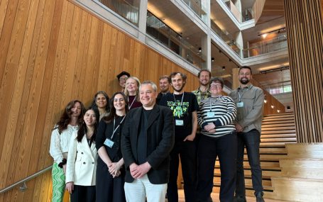 a group of 14 Phoneticians standing on a wooden staircase