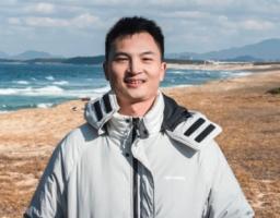 portrait of Chen Xie standing by a windy sea shore