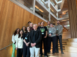 a group of 14 Phoneticians standing on a wooden staircase