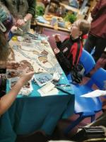 People around a table working on an unfinished blue, beige, and brown mosaic
