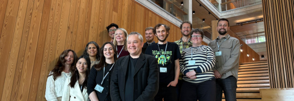 a group of 14 Phoneticians standing on a wooden staircase